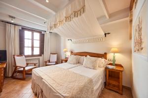 a bedroom with a bed and two chairs and a window at Casa Son Sant Jordi in Pollença