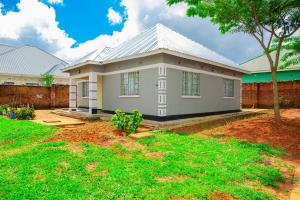 a small white house with a tree in the yard at The Private Home Mzuzu Area 4 Escape in Mzuzu