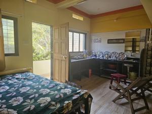 a room with a bed and a kitchen with a sink at SaiKrupa Homestay in Kudāl