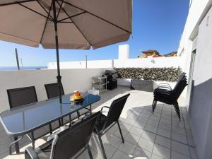 a patio with a table and chairs and an umbrella at La terraza de la Jaca in Arico