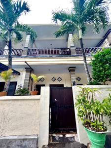 a house with a black gate and palm trees at OSA Guest House in Seminyak