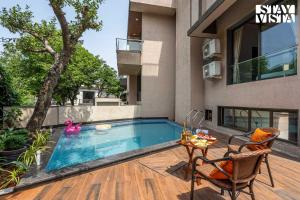 a swimming pool with a table and chairs next to a building at StayVista at Manthan with BBQ, Jacuzzi in Lonavala