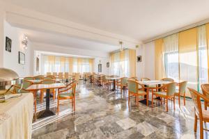 a dining room with tables and chairs and windows at Hotel Vila Marco Polo in Slatine