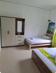 a bedroom with two beds and a dresser with a mirror at Evasion Maragon in Saint Gabriel