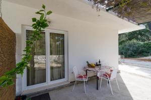 d'une terrasse avec une table, des chaises et une fenêtre. dans l'établissement Apartments Skurla, à Saplunara
