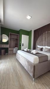 a bedroom with a large bed and green walls at Hotel Leodori 2 in Shëngjin