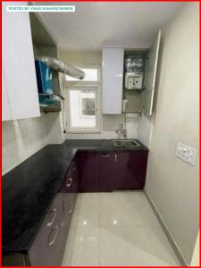 a small kitchen with purple cabinets and a window at Greenland Apartment in Pune