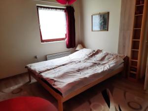 a bed sitting in a room with a window at Tahi Apartman in Tahitótfalu