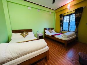 2 Betten in einem Zimmer mit grünen und gelben Wänden in der Unterkunft Hotel Lekhnath View Tower and Eco Farm in Deorāli