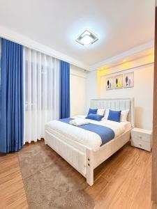 a bedroom with a large bed and blue curtains at Amari Suites in Gatunga