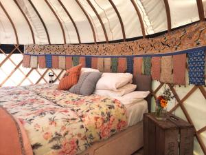 a bed in a yurt with a comforter and pillows at Glastonbury Wild Glamping in Glastonbury