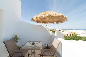a patio with chairs and an umbrella and the ocean at Dauti Gold Suites in Vóthon