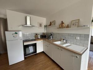 a kitchen with a white refrigerator and a sink at Le Refuge in Semide
