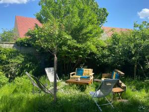 a garden with chairs and a table and a tree at Les Charmettes chambre double indépendante in Villemoisson-sur-Orge