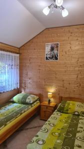 a bedroom with two beds in a room with wooden walls at Domki i Pokoje u Asi in Stegna