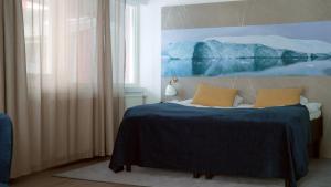 a bedroom with a bed with a painting on the wall at Hotel Arctic in Ilulissat