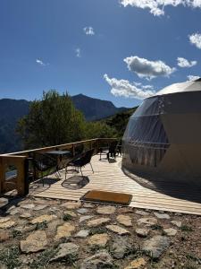 Una tienda de campaña situada en una terraza de madera con montañas al fondo. en Le dôme de Jèpo, en Ilonse