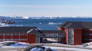 a red building with a view of the water at Hotel Arctic - 4 Star Superior in Ilulissat