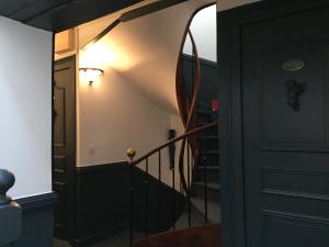 a hallway with a black door and a staircase at Hostellerie Normande in Houlgate