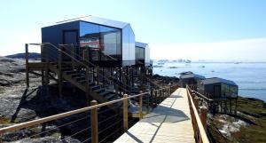 a building on the side of a hill next to the water at Hotel Arctic in Ilulissat