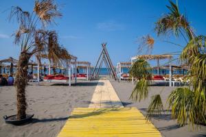 a wooden walkway on a beach with palm trees at Bahr DELUX App & Suite in Ulcinj