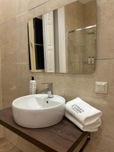 a bathroom with a white sink and a mirror at Vestígios de Charme - Figueira Suits in Figueira da Foz +20 photos