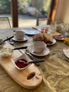 Una mesa de madera cubierta con tazas, platillos y comida. en Green House B & B, en Villa La Angostura