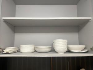 a shelf with white bowls and plates on it at Kasukabe raku house in Kasukabe