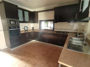 a large kitchen with black cabinets and a sink at Casa das Marinhas in Caminha