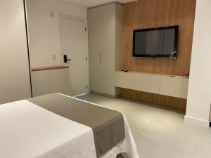 una camera da letto con un letto e una TV a schermo piatto di LOFT Ed Carbono a Blumenau