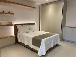 una piccola camera da letto con un letto con una coperta bianca di LOFT Ed Carbono a Blumenau