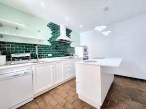 a kitchen with white cabinets and green subway tiles at BHost - Palace in Córdoba