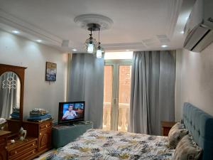 a bedroom with a bed and a tv and a window at 378 Pyramids St -Two bedrooms Hotel Apartment in Cairo