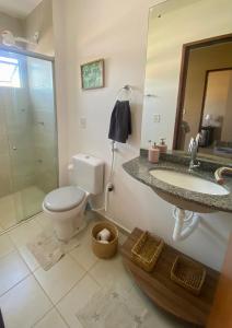 a bathroom with a toilet and a sink and a mirror at Casa Paraiso Beira-Mar in Maracajaú