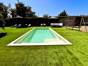 Una piscina en un patio con césped y un área de juegos para niños. en Mas de la Maria, en Cambrils