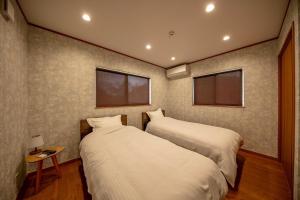 Dos camas en una habitación con dos ventanas. en ソレイユ白浜, en Shirahama