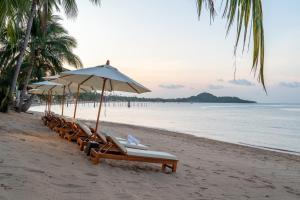 a group of lounge chairs and umbrellas on a beach at Baan Bophut Beach Hotel Samui - SHA Extra Plus in Bophut