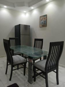 a glass table with three chairs and a refrigerator at 378 Pyramids St -Two bedrooms Hotel Apartment in Cairo