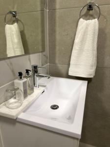 a bathroom with a white sink and a mirror at Waterfall Luxury Apartment in Midrand