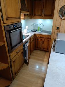 a small kitchen with wooden cabinets and a tv at La maison du prieur in Langogne