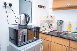 a microwave on top of a refrigerator in a kitchen at Serene Getaway Studio Along Ngong road-Nairobi,Kenya in Nairobi