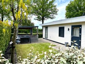 a white shed with a picnic table in a yard at Ruimte, privacy en comfort op de Veluwe, inclusief 2 fietsen & linnengoed in Nunspeet
