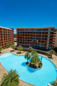 Una gran piscina con palmeras frente a un edificio. en Boho Apartment, en Mai Khao Beach