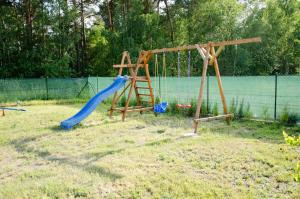 a playground with two swings and a slide at Domki z basenem & kajaki u Krysi in Borne Sulinowo