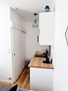 eine Küche mit weißen Schränken und einer Spüle in der Unterkunft Studio 1 Cozy en centre-ville - Puy duFou in Les Herbiers
