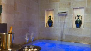 a bath tub with blue water in a room with vases at Victory Suite in Monopoli