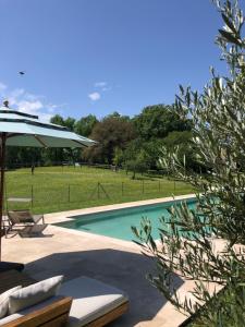 a swimming pool with a table and an umbrella at Le Buscagneau in Béraut