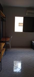 a room with a bed and a chair and a window at Quarto independente em casa de família com banheiro fora da habilitação mas é privado in Santos