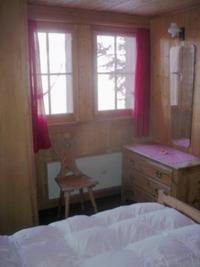 ein Schlafzimmer mit einem Bett, einer Kommode und zwei Fenstern in der Unterkunft Chalet Edith Oberems in Oberems