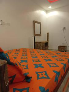 a bedroom with a large bed with an orange comforter at Lamaisu Homes Block 3 in Abuja